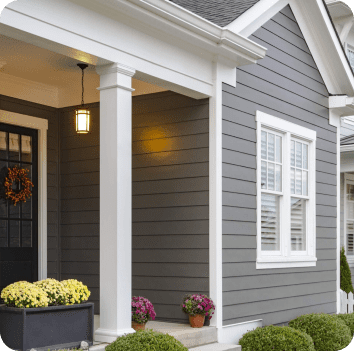 image of the front porch and front window of a suburban house with grey vinyl siding and white trim
