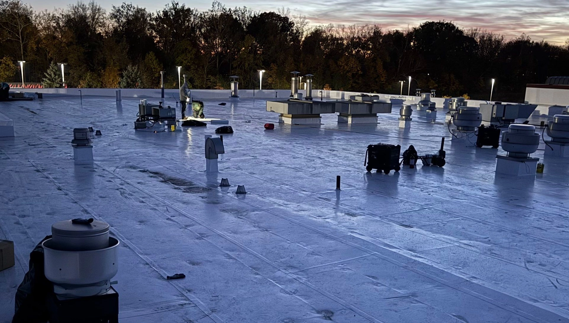 Evening durolast roof installation with lights and equipment on the roof